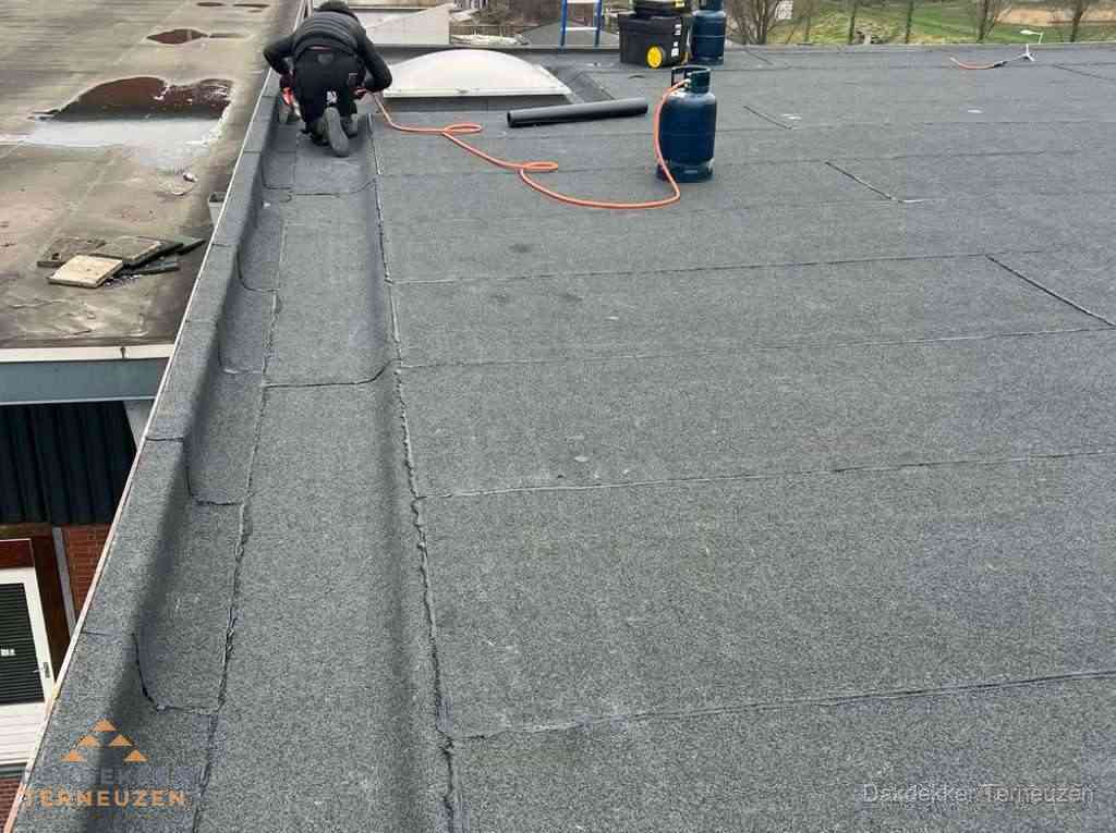 Dakdekker repareert bitumen dakbedekking op groot plat dak in Terneuzen